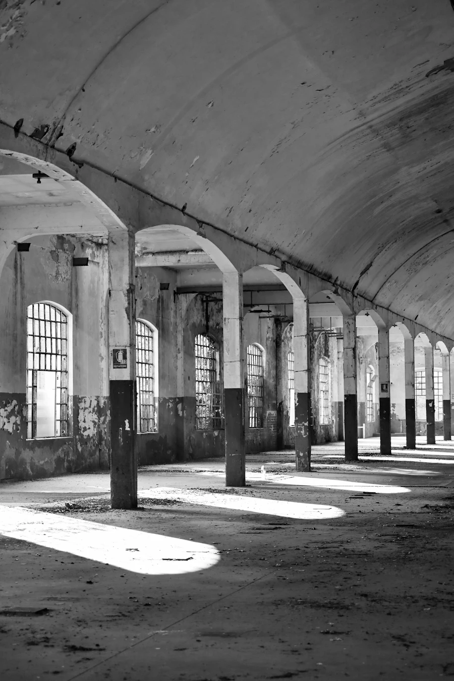 Long arched industrial hall in black and white with light falling through high windows